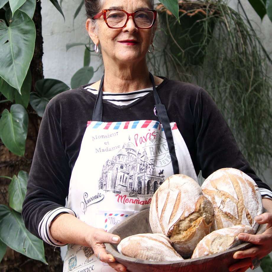 A Su no quintal, segurando a gamela com os pães do dia